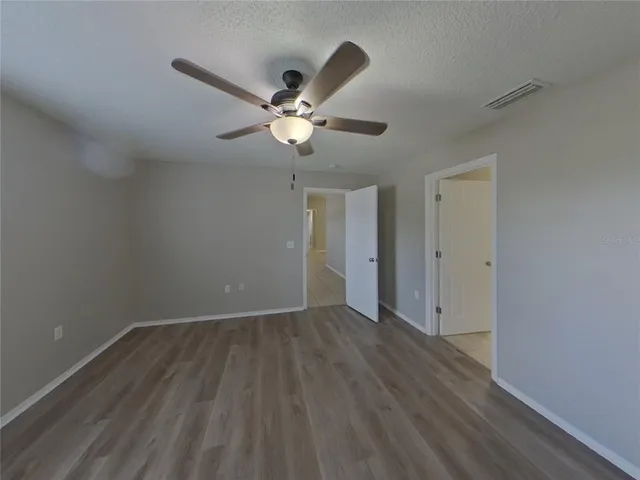 an empty room with wooden floor and ceiling fan