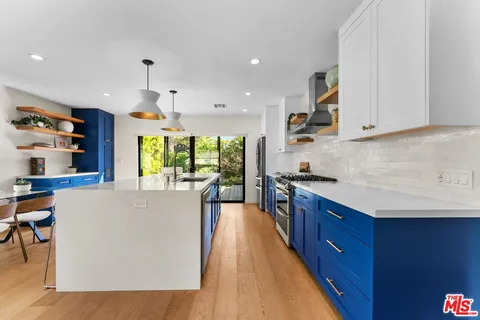 a large kitchen with stainless steel appliances granite countertop a stove a sink dishwasher and a refrigerator with wooden floor