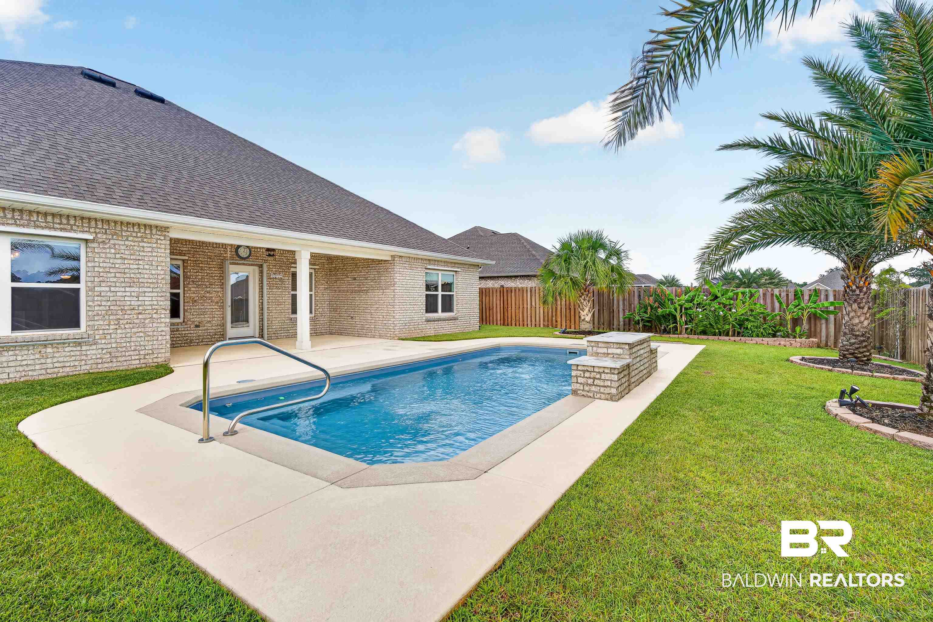 1724 Partridge Street Foley, AL 36535 - Photo 54 of 62 Backyard featuring an in-ground swimming pool with stone coping, a surrounding concrete patio, and a covered porch