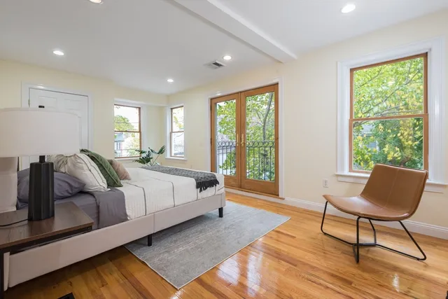 a spacious bedroom with a bed a chair and next to a window