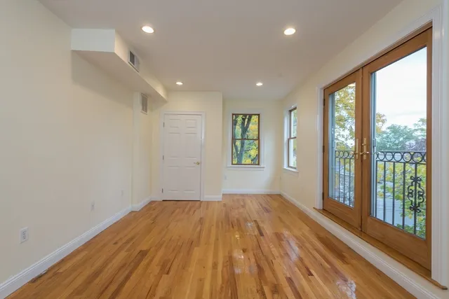 a view of empty room with wooden floor and fan