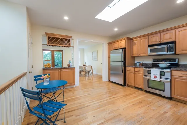 a kitchen with stainless steel appliances granite countertop a refrigerator a stove a sink dishwasher a dining table and chairs with wooden floor