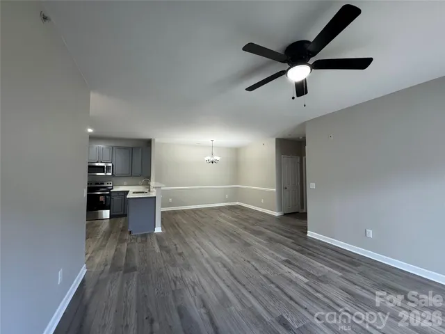 an empty room with wooden floor a ceiling fan and windows