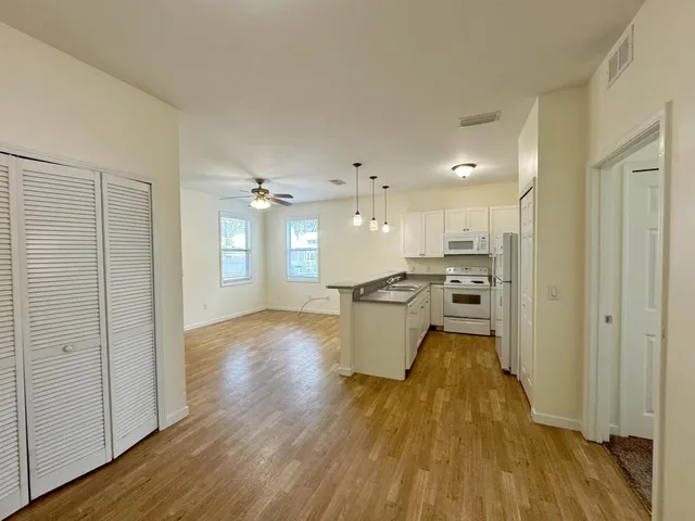 a open kitchen with white cabinets and wooden floor