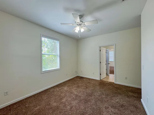 an empty room with windows and fan