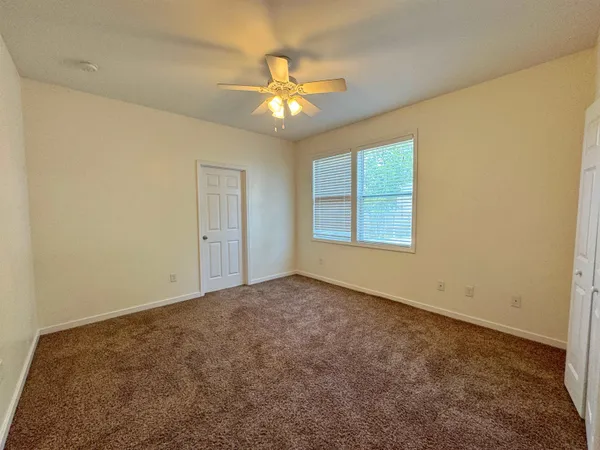 an empty room with windows and chandelier fan