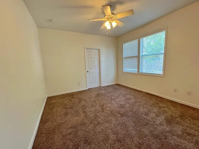 an empty room with windows and fan