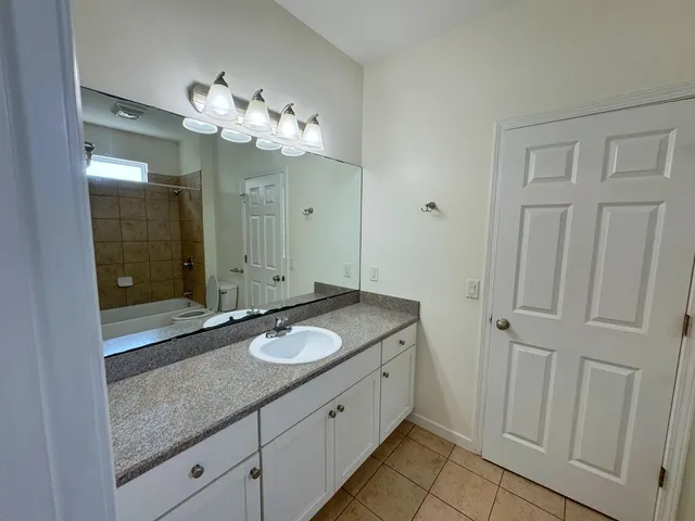 a spacious bathroom with a granite countertop sink a mirror and a shower