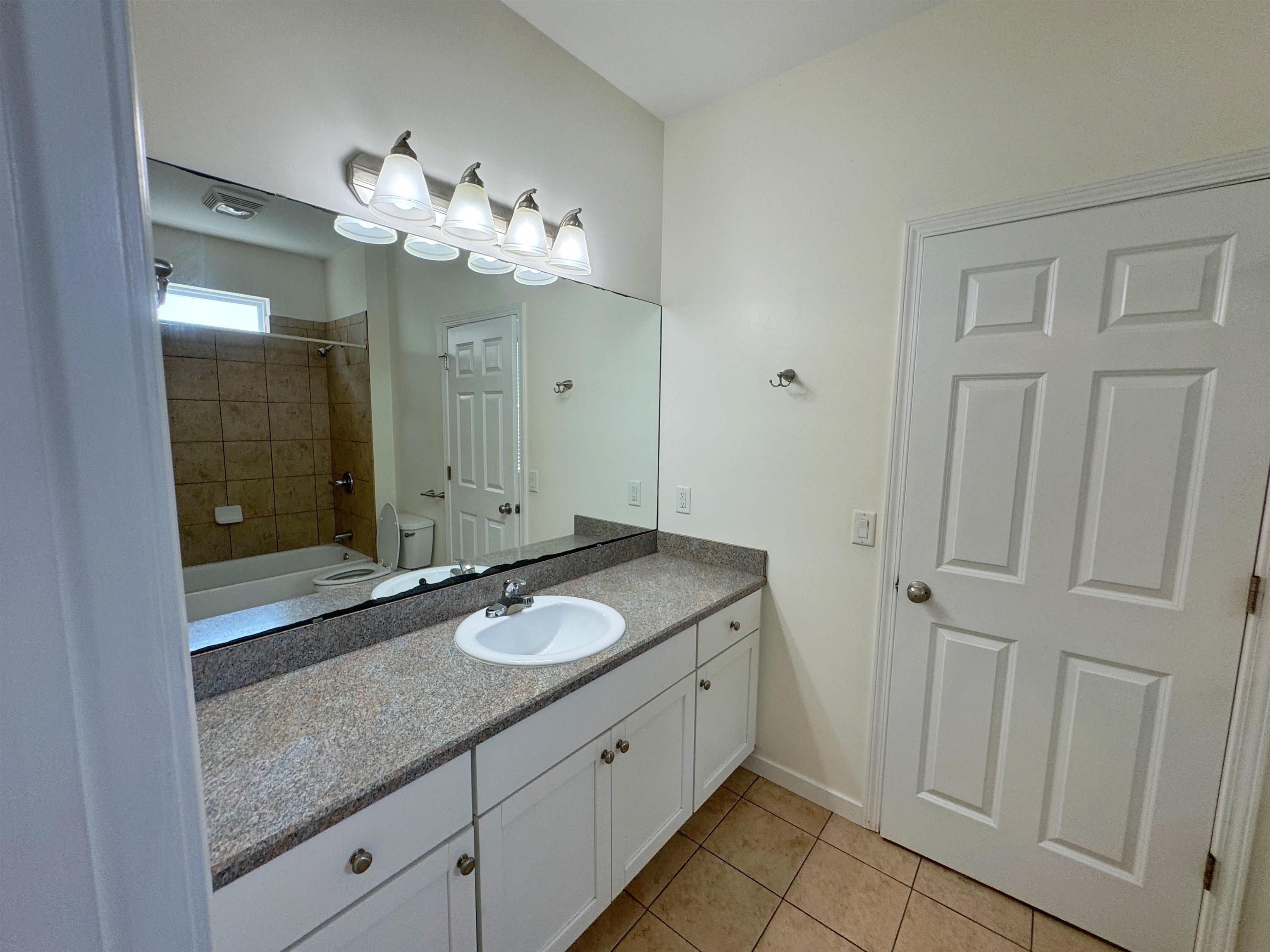 38 Weeden Street, Unit A St. Augustine, FL 32084 - Photo 24 of 29 a spacious bathroom with a granite countertop sink a mirror and a shower