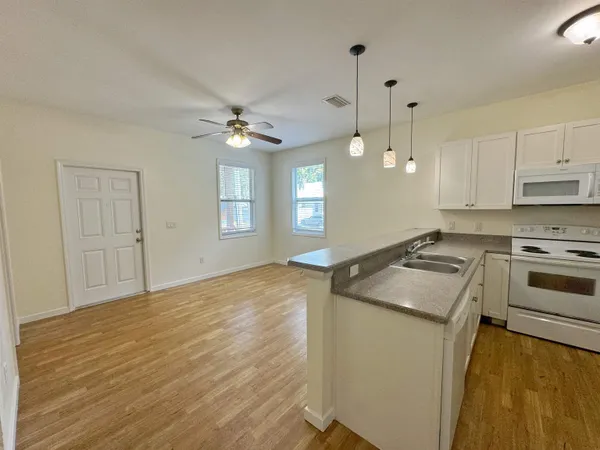 a kitchen with granite countertop a sink stainless steel appliances and white cabinets