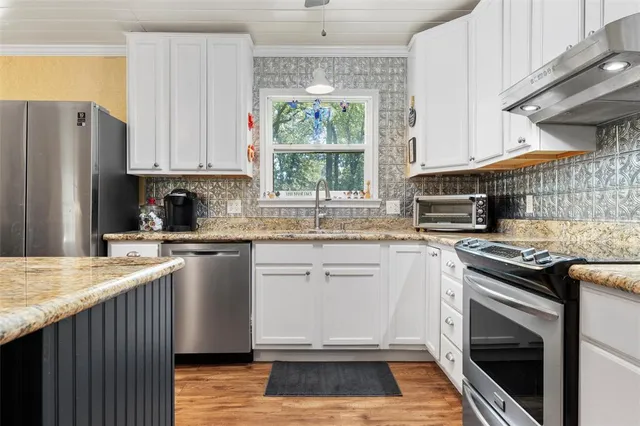 a kitchen with granite countertop a stove a sink dishwasher and a refrigerator