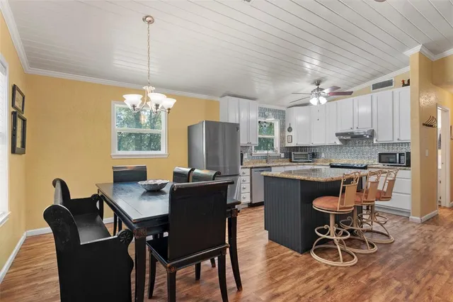 a kitchen with a dining table chairs and refrigerator
