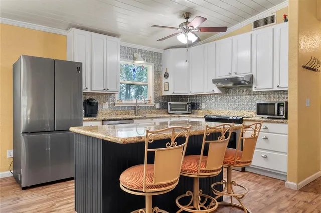 a kitchen with stainless steel appliances a table chairs refrigerator and sink