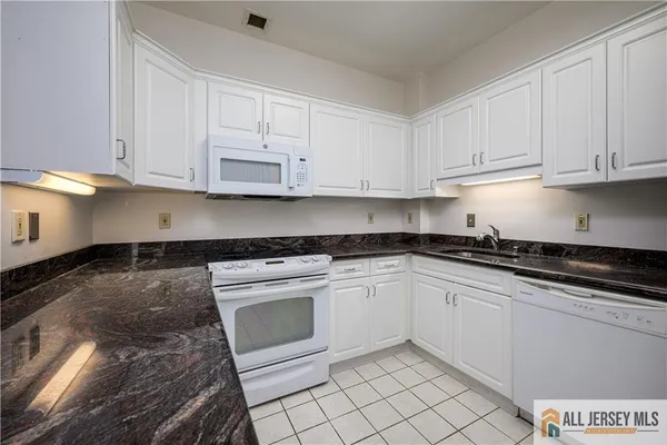a kitchen with granite countertop white cabinets and stainless steel appliances