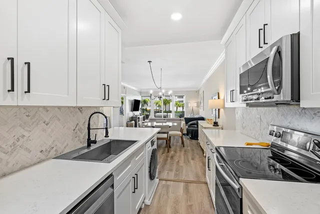 a kitchen with stainless steel appliances a sink a stove top oven a counter space and cabinets