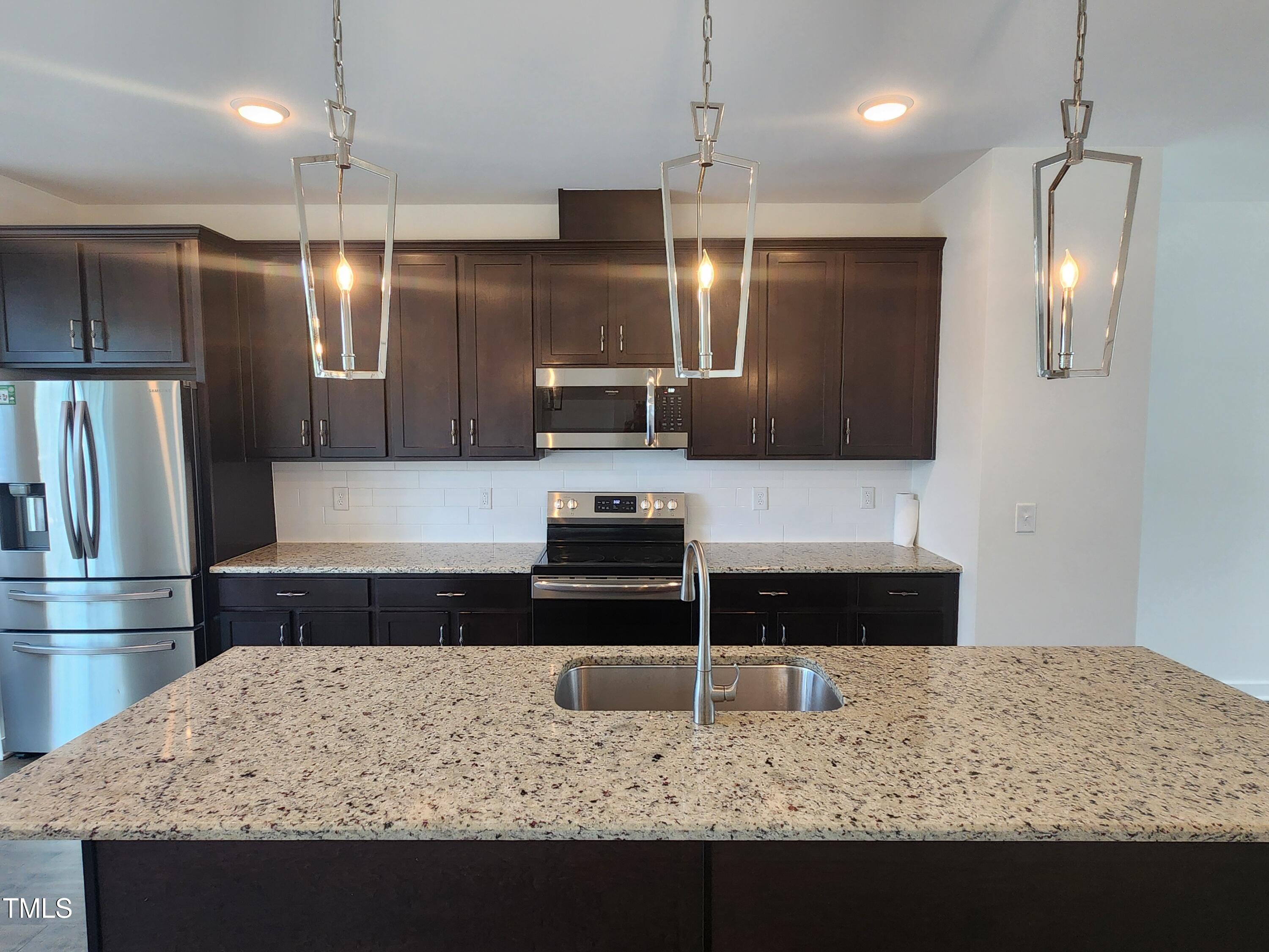 433 Rally Point Place Wake Forest, NC 27587 - Photo 3 of 15 a kitchen with kitchen island sink refrigerator and stove