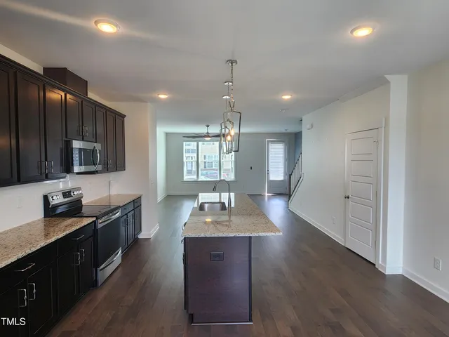 a kitchen with granite countertop wooden cabinets a sink dishwasher and a stove with wooden floor