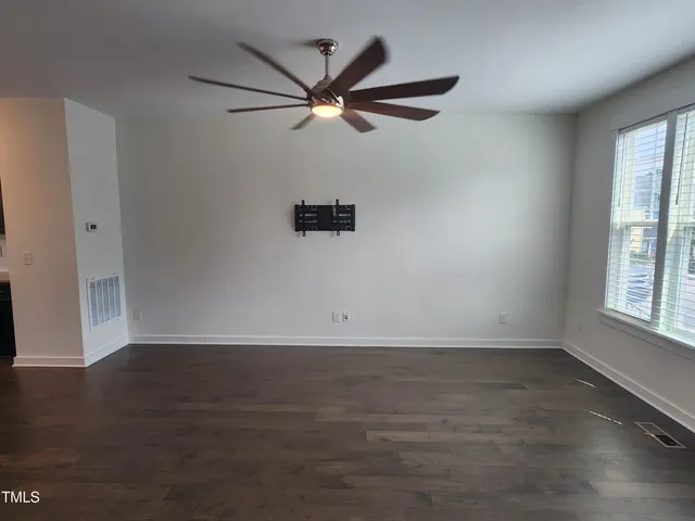 an empty room with wooden floor fan and windows