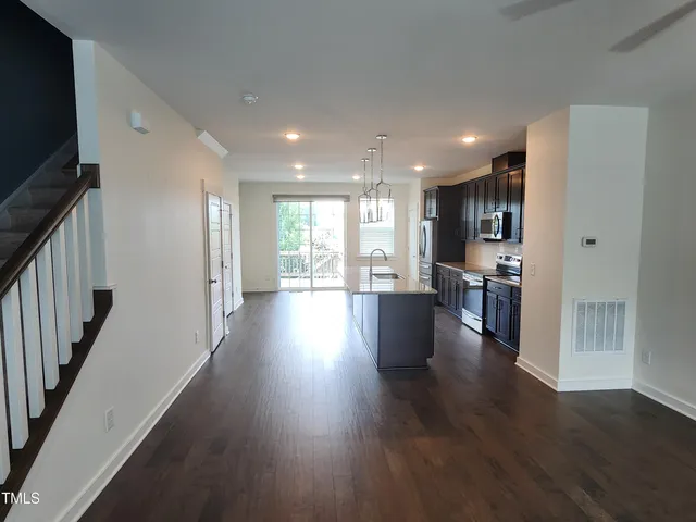 a view of a big room with wooden floor and a kitchen