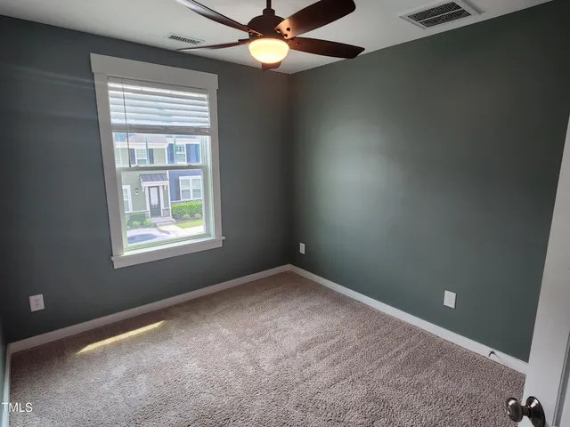 an empty room with a window and a fan