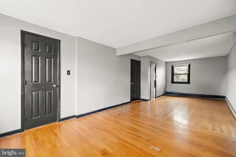 a view of an empty room with window and wooden floor