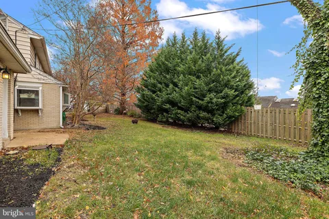 a view of a house with a large tree and wooden fence