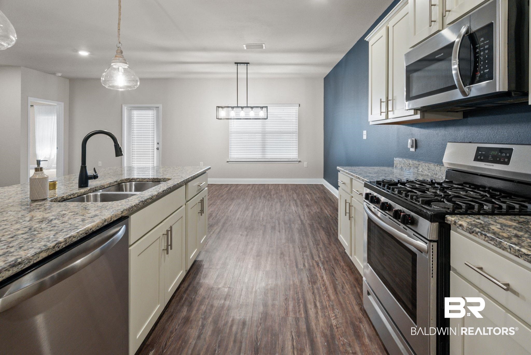 24769 Slater Mill Road Daphne, AL 36526 - Photo 9 of 38 Kitchen with stainless steel appliances, dark hardwood / wood-style flooring, hanging light fixtures, sink, and light stone counters
