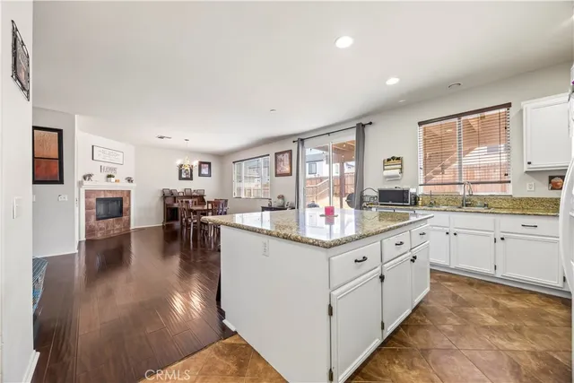 a kitchen with granite countertop lots of white cabinets and wooden floor