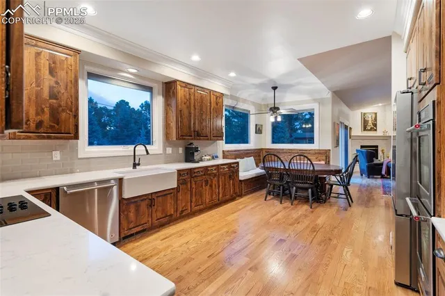 a kitchen with stainless steel appliances kitchen island granite countertop a table chairs sink and cabinets