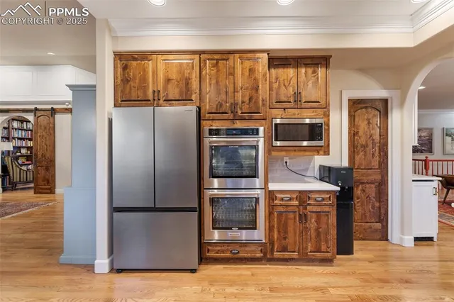 a kitchen with stainless steel appliances granite countertop a refrigerator a stove and a sink with wooden floor