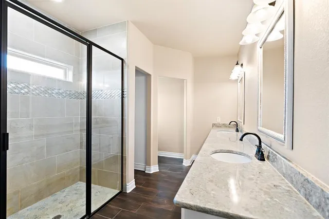 a bathroom with double sink large mirror and a window