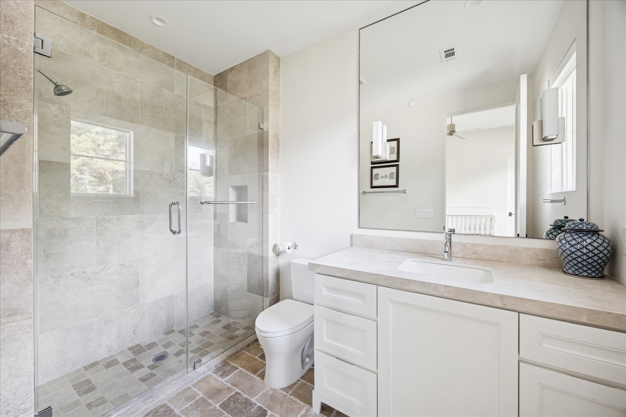 7 Hedwig Shadows Lane Houston, TX 77024 - Photo 28 of 46 A beautifully appointed guest bath with stone tile flooring, frameless glass shower, and sleek vanity. The soothing color palette mirrors the home’s overall sense of refinement and balance.
