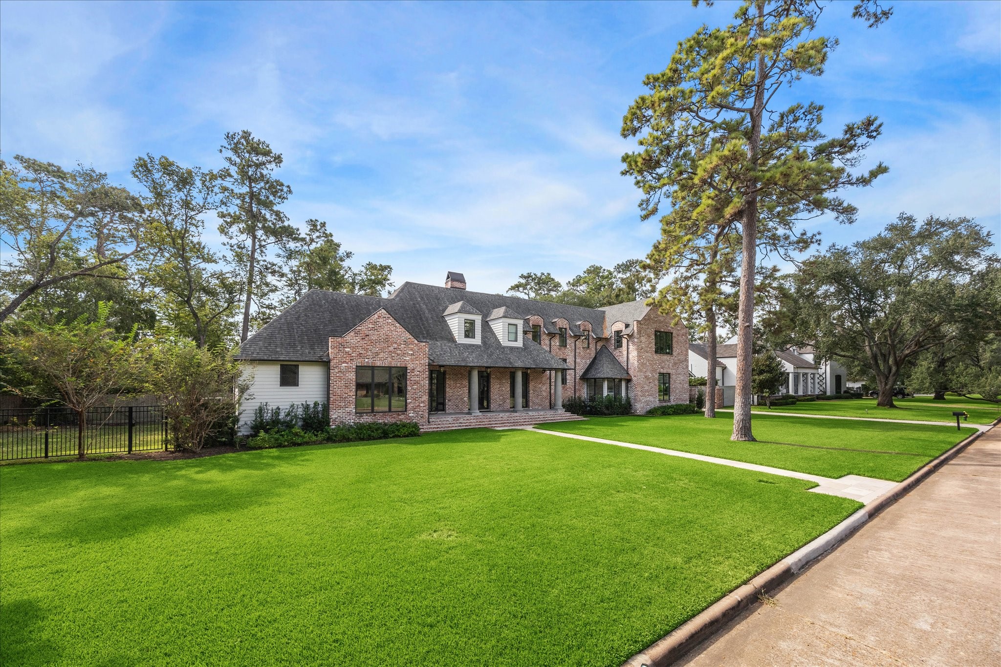 7 Hedwig Shadows Lane Houston, TX 77024 - Photo 44 of 46 Positioned on a quiet, tree-lined street, this residence commands attention with its classic materials and stately presence. The combination of reclaimed brick, limestone accents, and metal-clad windows create a façade that feels both substantial and inviting.