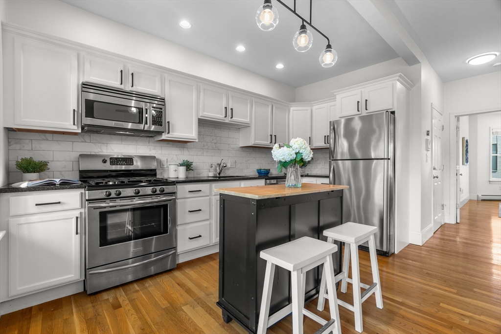 15 I Street, Unit 3 Boston, MA 02127 - Photo 2 of 17 a kitchen with stainless steel appliances a stove a sink refrigerator and a refrigerator with wooden floor