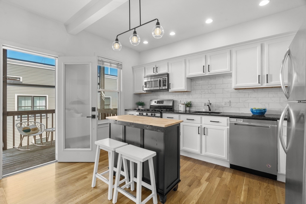 15 I Street, Unit 3 Boston, MA 02127 - Photo 5 of 17 a kitchen with stainless steel appliances granite countertop a stove a sink dishwasher a refrigerator and white cabinets with wooden floor
