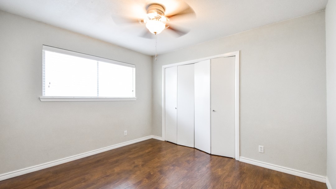 910 Rocky Spring Road Austin, TX 78753 - Photo 22 of 26 an empty room with wooden floor fan and windows