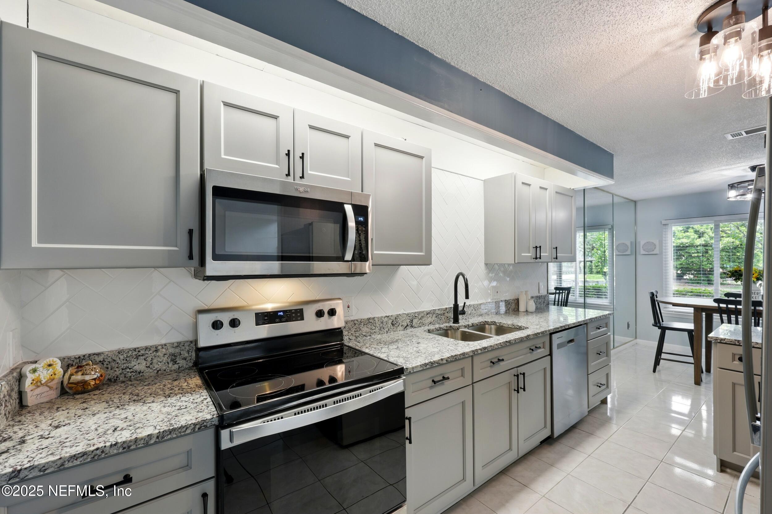 9360 Craven Road, Unit 1406 Jacksonville, FL 32257 - Photo 14 of 30 a kitchen with granite countertop a sink and a stove top oven