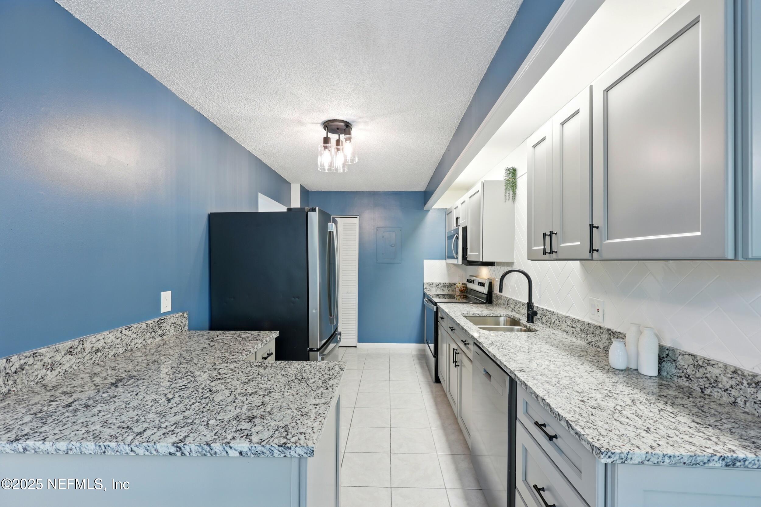 9360 Craven Road, Unit 1406 Jacksonville, FL 32257 - Photo 15 of 30 a kitchen with stainless steel appliances granite countertop a sink stove and refrigerator