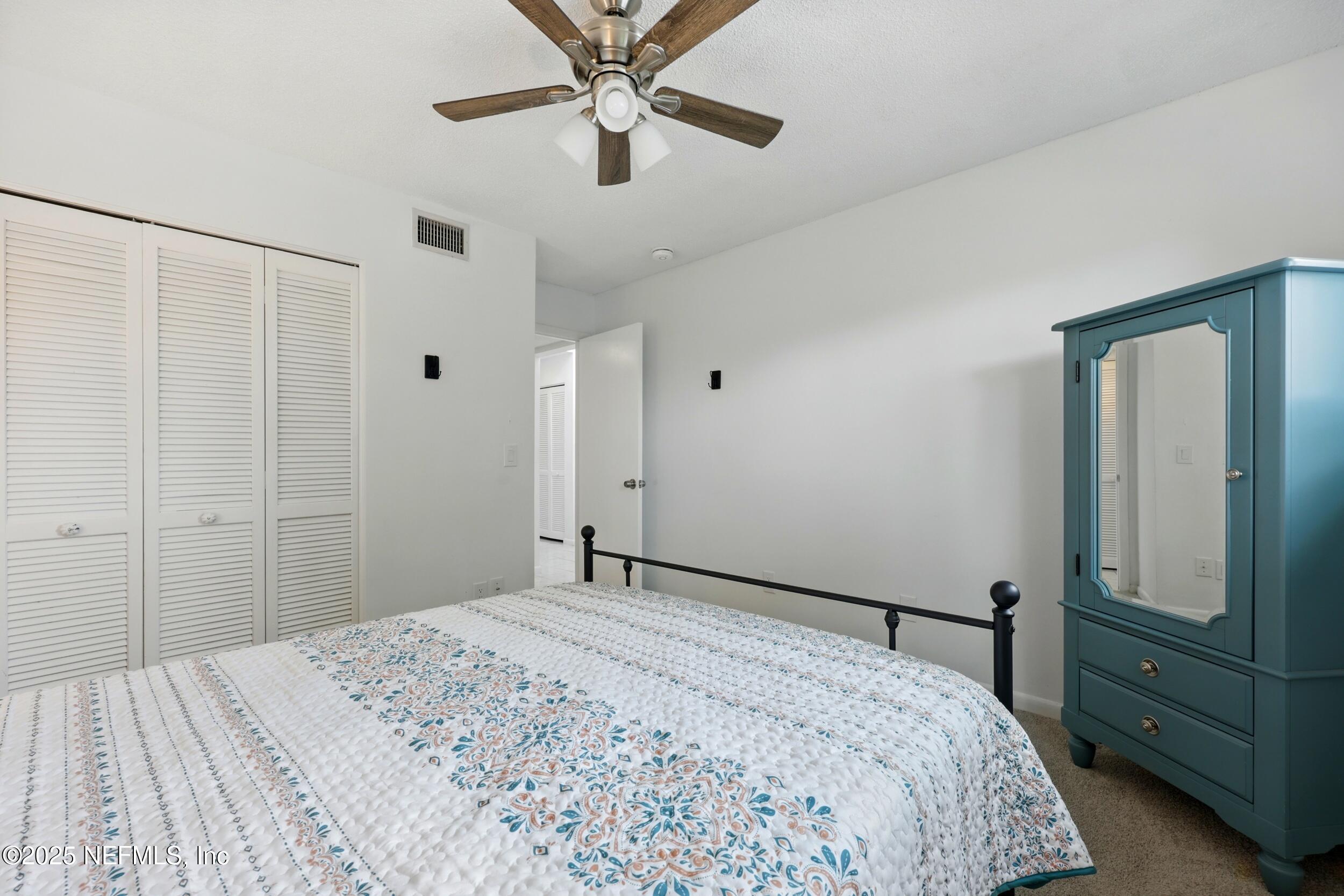 9360 Craven Road, Unit 1406 Jacksonville, FL 32257 - Photo 23 of 30 a bedroom with a large bed and a chandelier