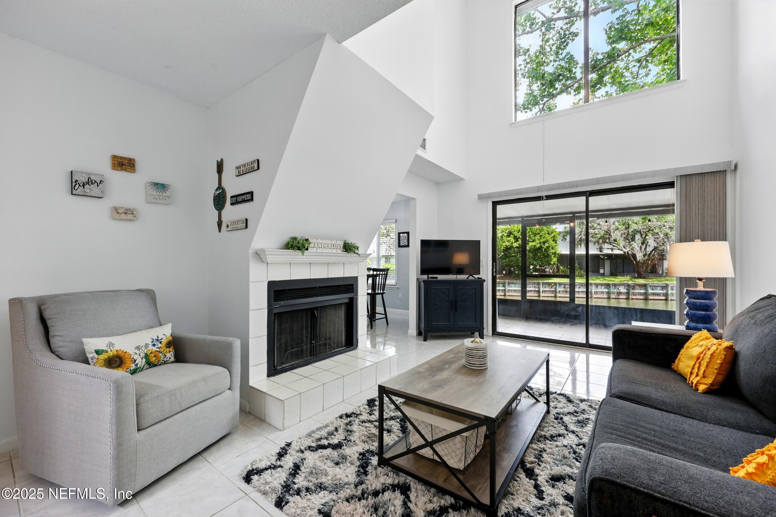 9360 Craven Road, Unit 1406 Jacksonville, FL 32257 - Photo 3 of 30 a living room with furniture a fireplace and a floor to ceiling window
