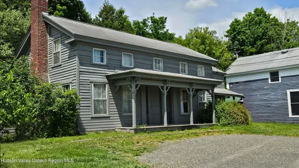 a view of brick house with a yard plants and large tree