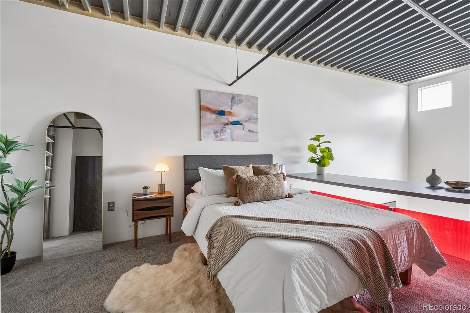 3457 Ringsby Court, Unit 347 Denver, CO 80216 - Photo 12 of 22 a bedroom with a bed and a chandelier