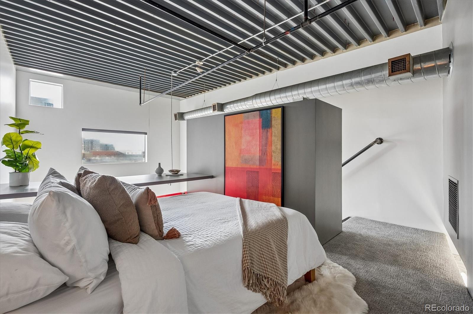 3457 Ringsby Court, Unit 347 Denver, CO 80216 - Photo 13 of 22 a bedroom with bed and a walk in closet