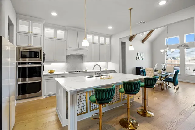 a kitchen with stainless steel appliances granite countertop a stove a refrigerator a kitchen island a dining table and chairs with wooden floor