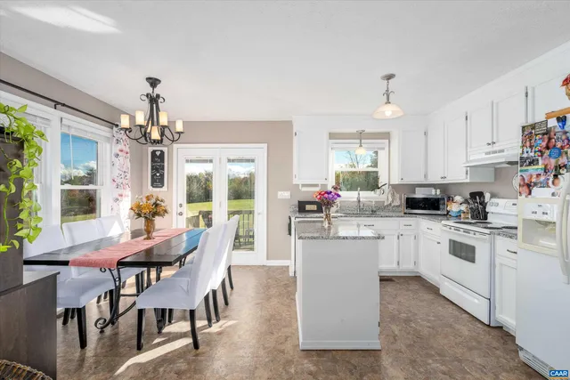 a kitchen that has a lot of white cabinets and stainless steel appliances
