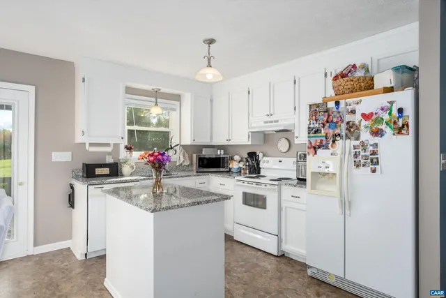 a kitchen with stainless steel appliances granite countertop a refrigerator a sink dishwasher and white cabinets with wooden floor