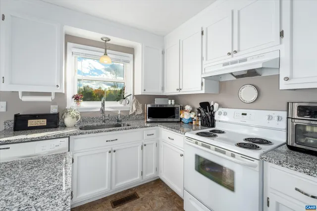 a kitchen with granite countertop white cabinets and white appliances