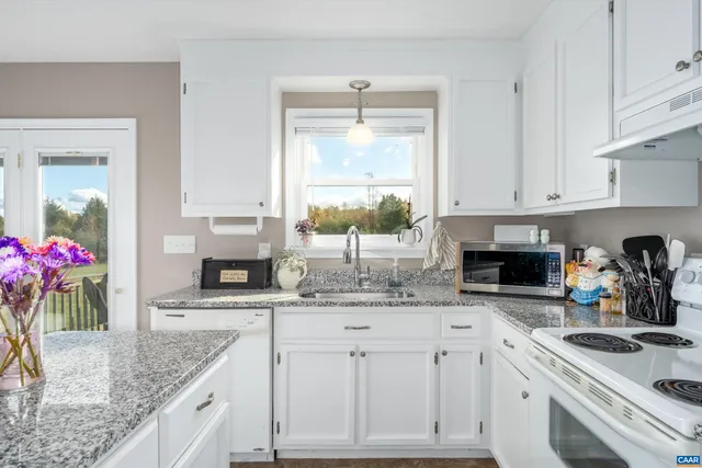 a kitchen with granite countertop a sink stove and cabinets