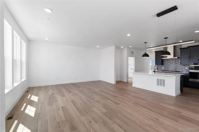 a view of kitchen with kitchen island wooden floors stainless steel appliances and window