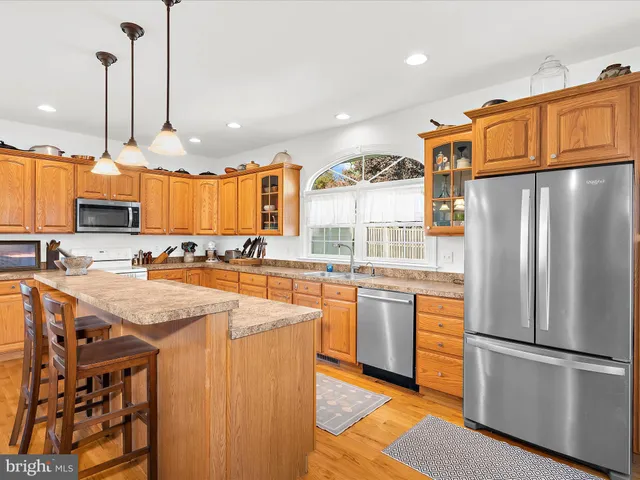 a kitchen with stainless steel appliances granite countertop a refrigerator a stove and a sink with wooden floor